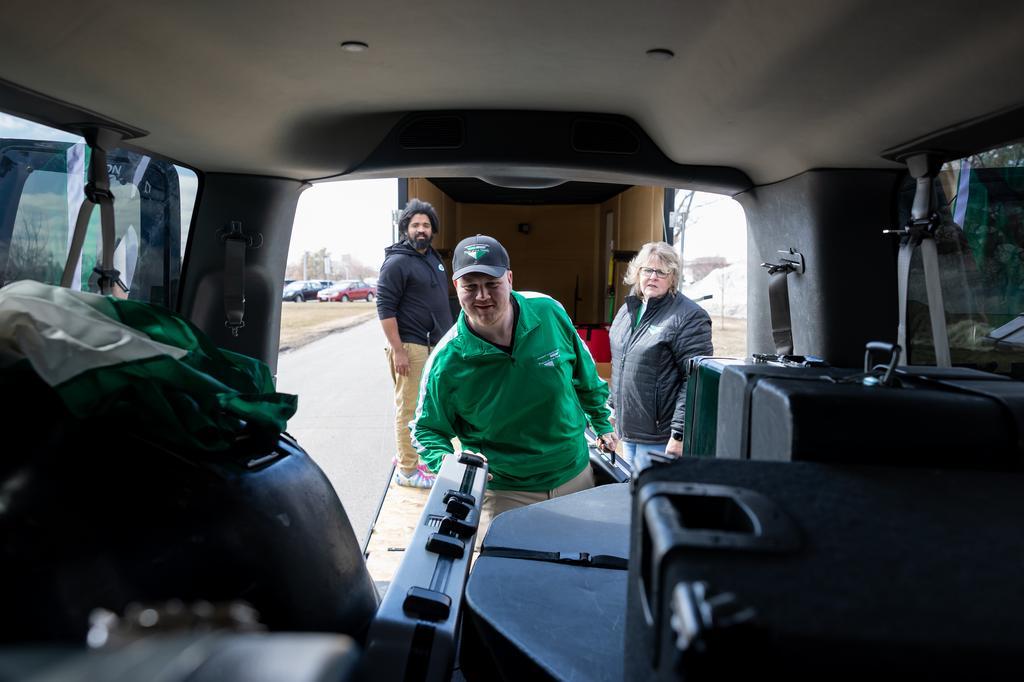 three people packing instruments into a van