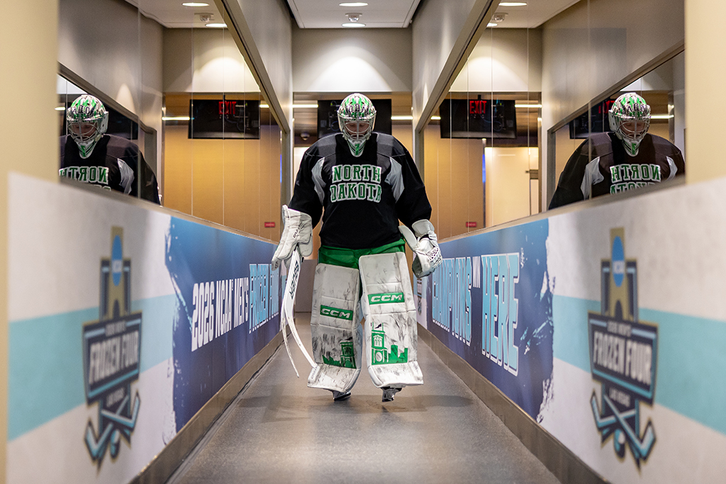 Goalie in practice gear walks through corridor to the rink