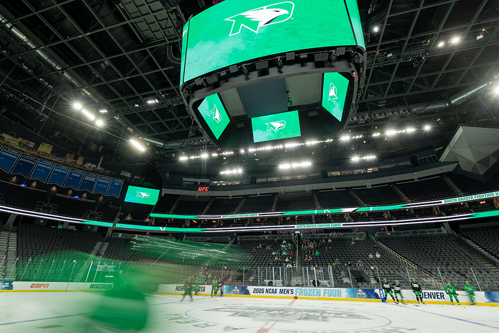Skater blurs past in foreground with Fighting Hawks logo displayed on scoreboards above