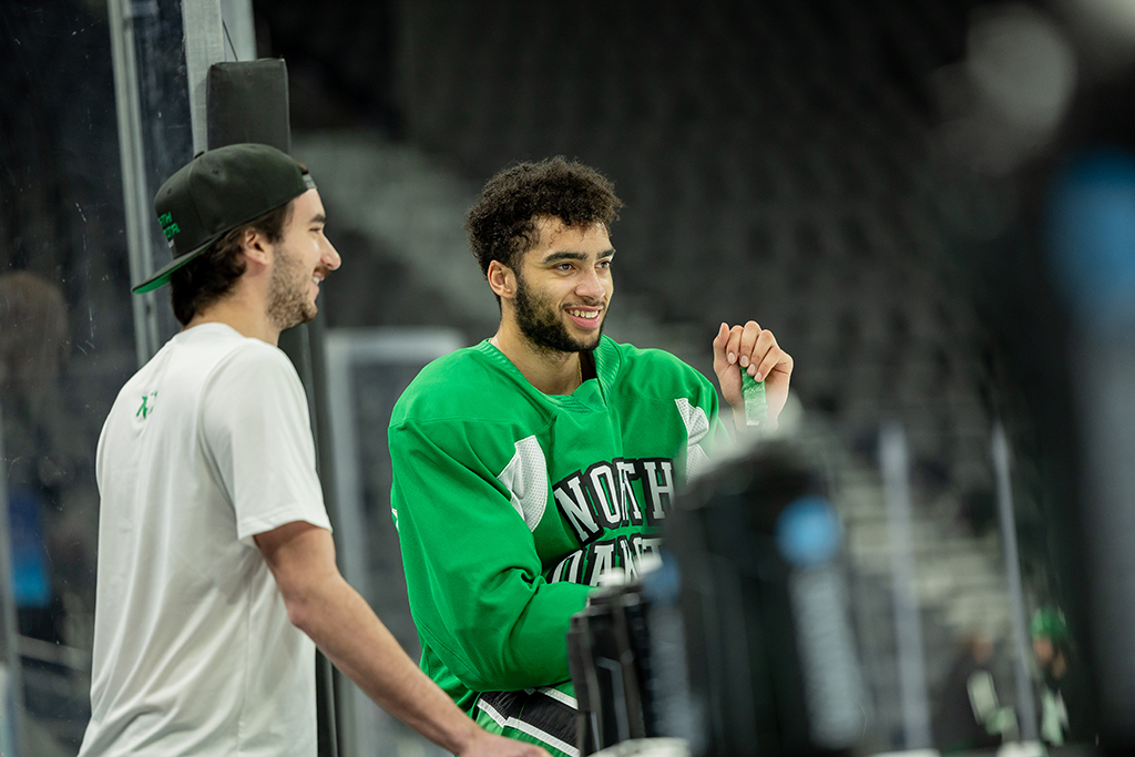 Player in practice gear chats with someone standing near the bench