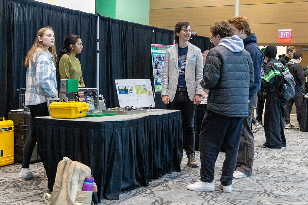 students talking to faculty member at booth.