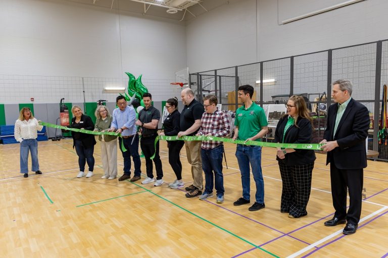 UND faculty and officials line up for ribbon cutting in facility gymnasium.