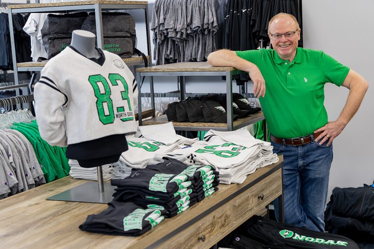 Man stands by display of UND-branded clothing in UND bookstore.