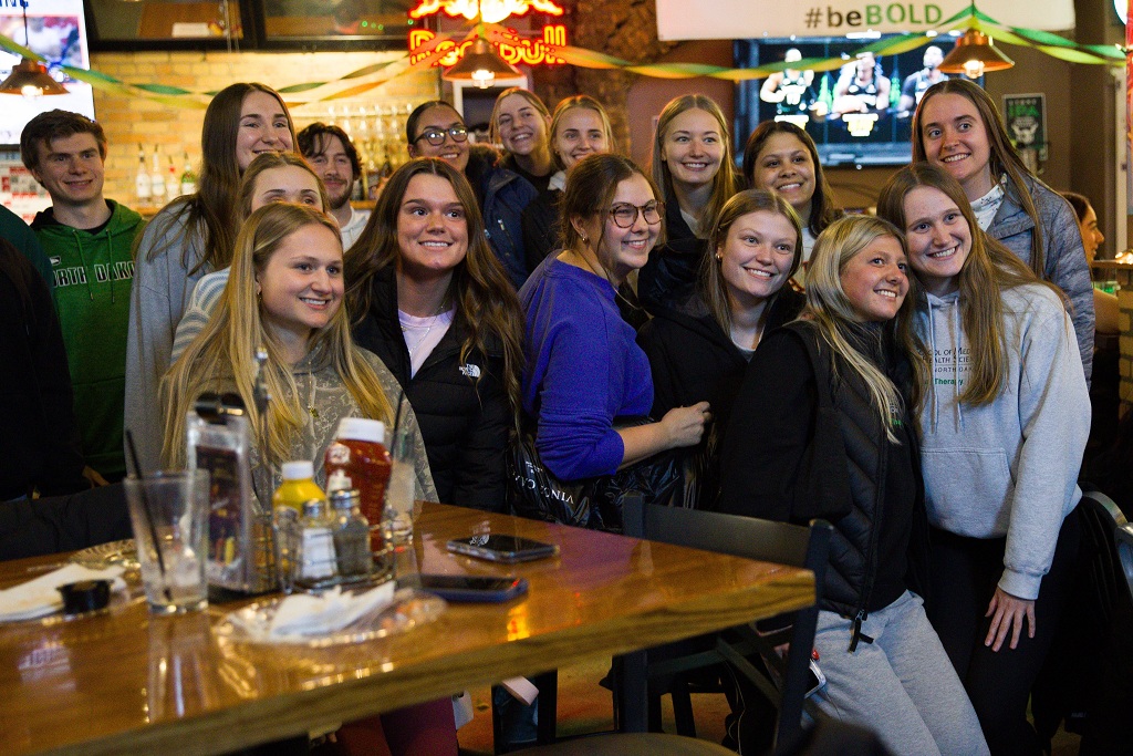 Group of students in Brick & Barley pub smile for photographer.
