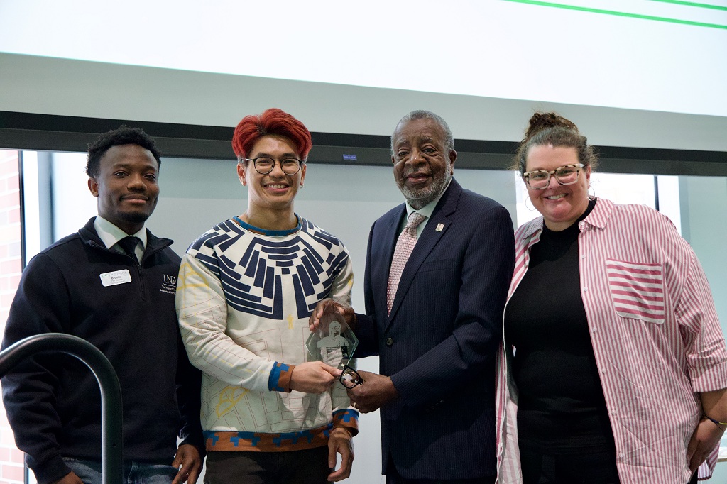 Four people stand side by side, posing for photo