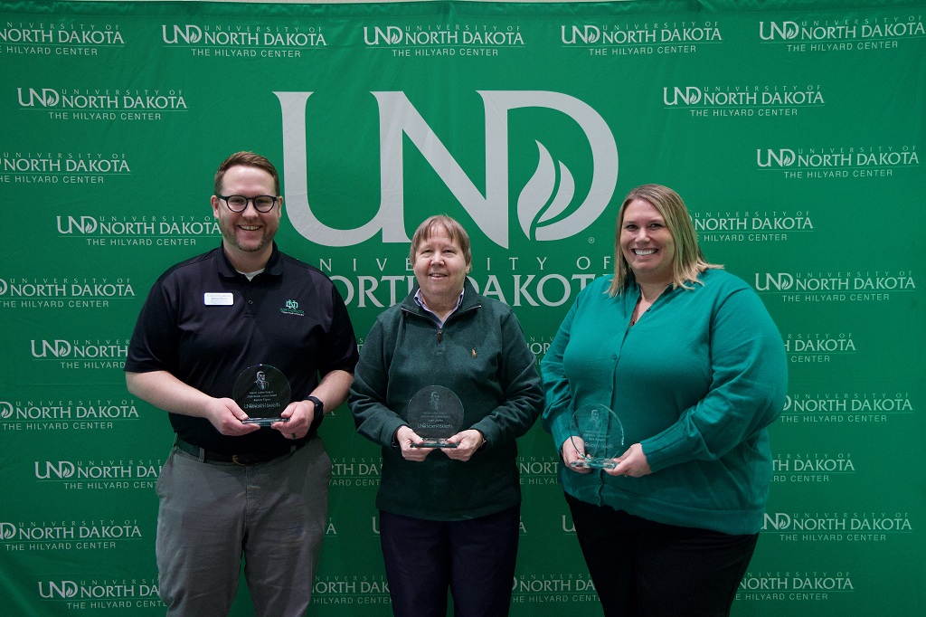 Four people stand in line with their UND awards