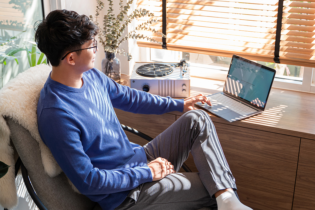 Person sitting at desk, leg crossed, using laptop