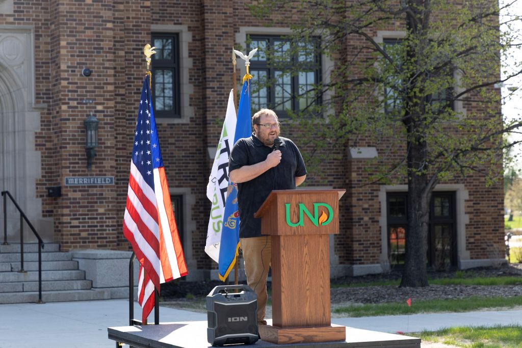 Jared Johnson speaks at a podium outside Merrifield Hall during UND’s Arbor Day celebration.