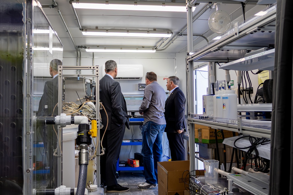 Three men examining inside of trailer housing Divergent Wastewater Treatment Facility at UND.