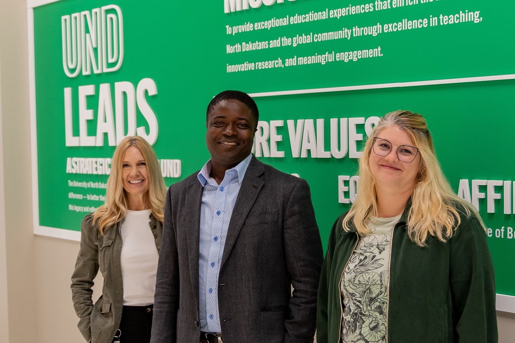 Three UND employees stand in front of the UND LEADS backdrop in the Memorial Union