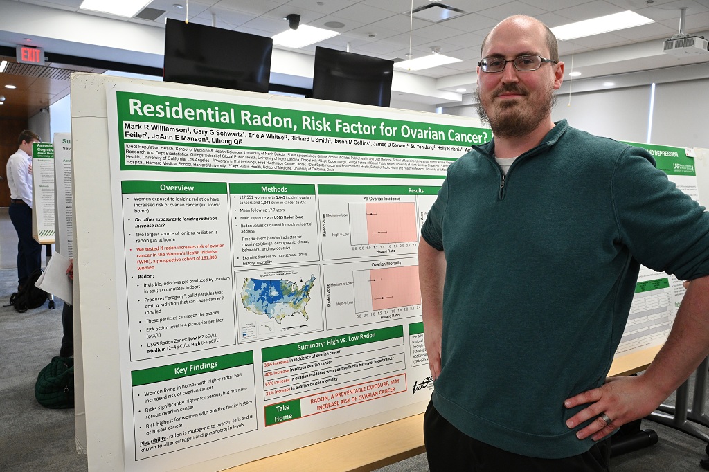 Man stands with research poster at UND conference