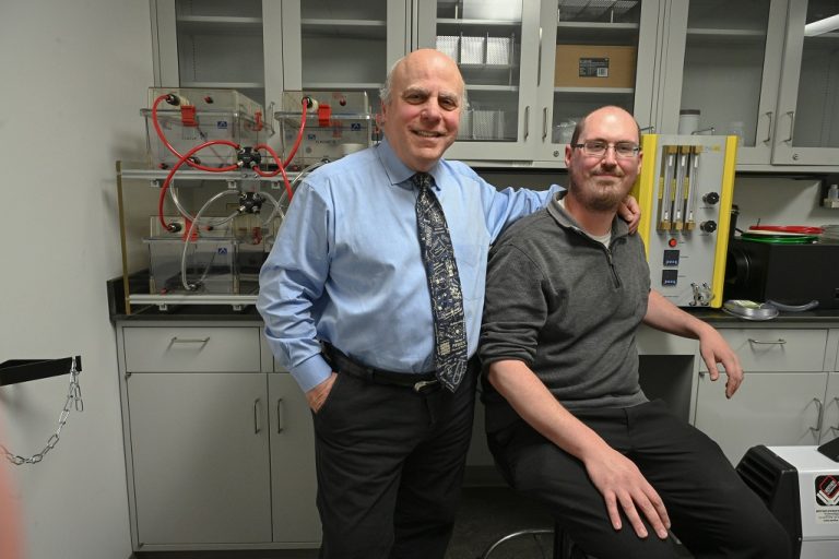 Two man stand next to each other in a lab