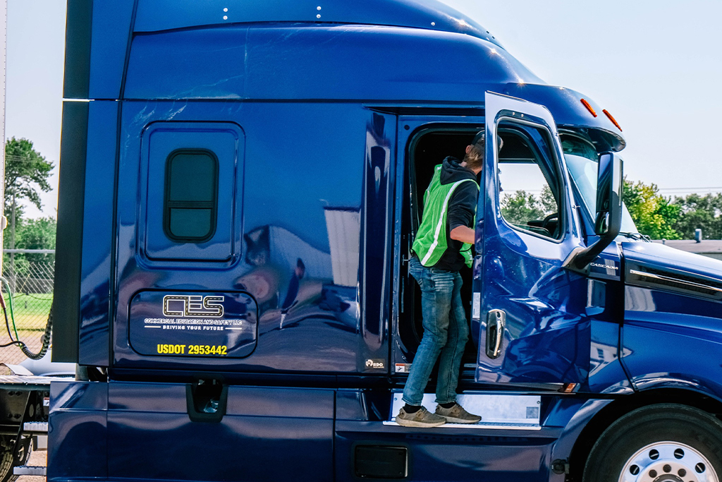 Person in high-visibility vest entering truck cab.