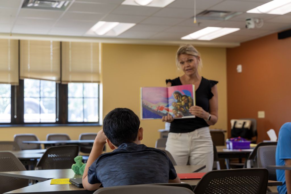 A student looks at a book presented by his teacher Mrs. Lowe.