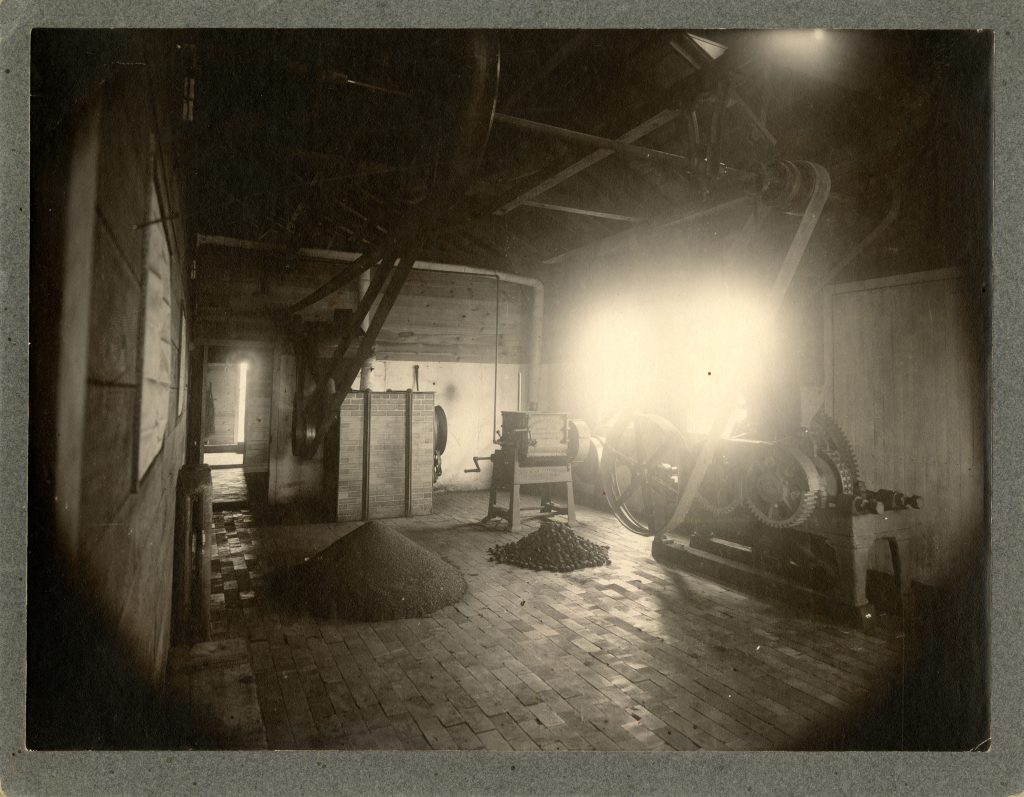 Historic black-and-white photograph of the University of North Dakota's lignite coal research facility, showing early coal processing machinery and piles of lignite inside the building.