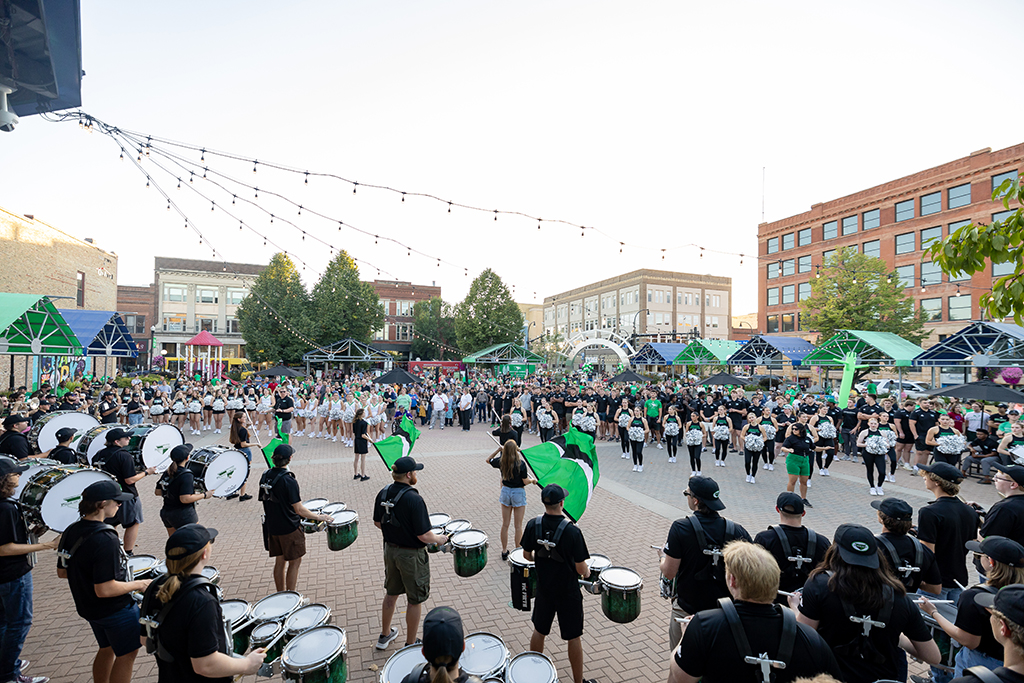 UND marching band in formation playing in front of crowd at town square