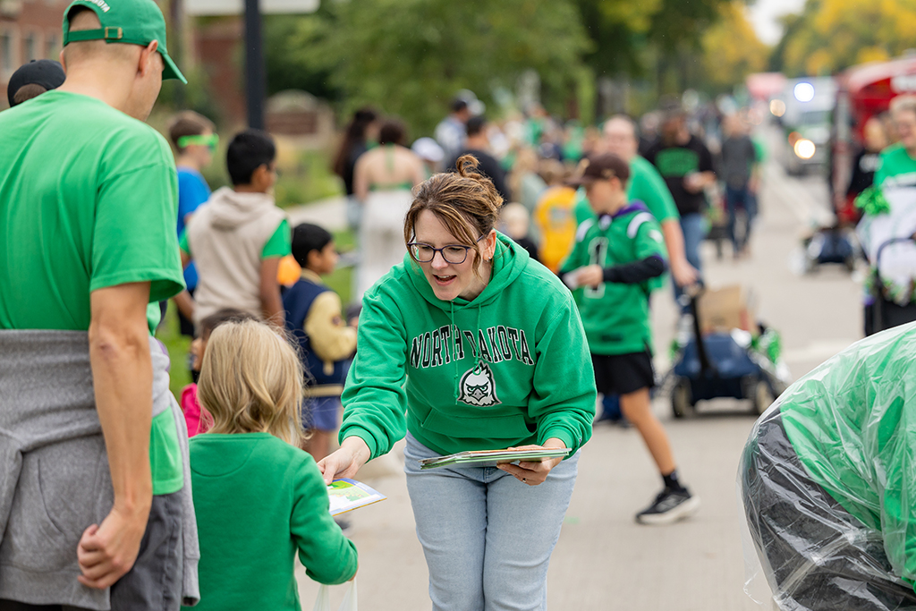 Person handing out booklet to child during parade