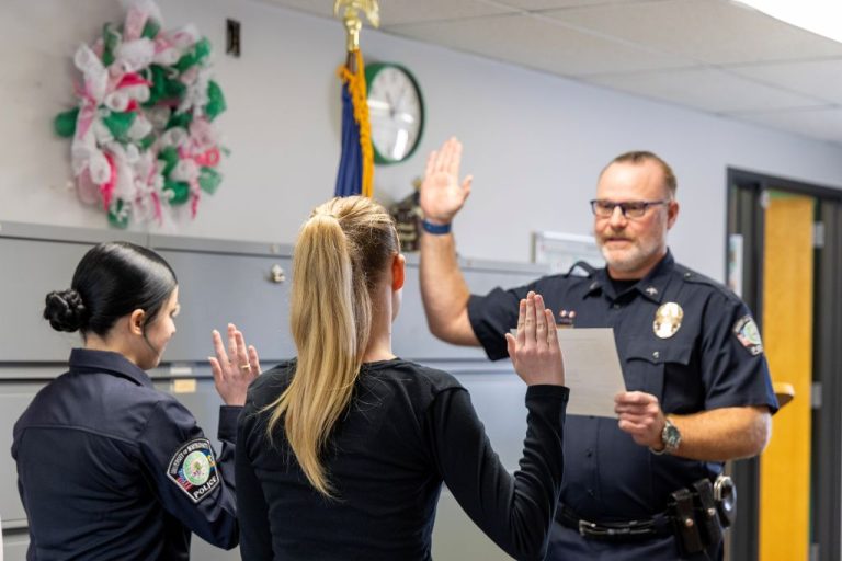 Josie Beltz and Febee Harlow raise their right hands while UND Police Chief Rodney Clark reads the oath of office.