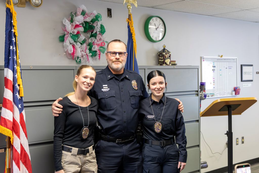 Josie Beltz and Febee Harlow stand on either side of UND Police Chief Rodney Clark, wearing their badges.