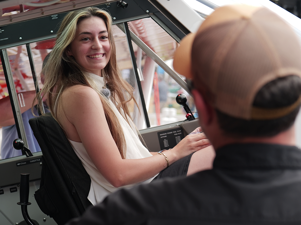 Ashley Almquist smiles while sitting in the pilot’s seat of an Aviat Husky airplane.