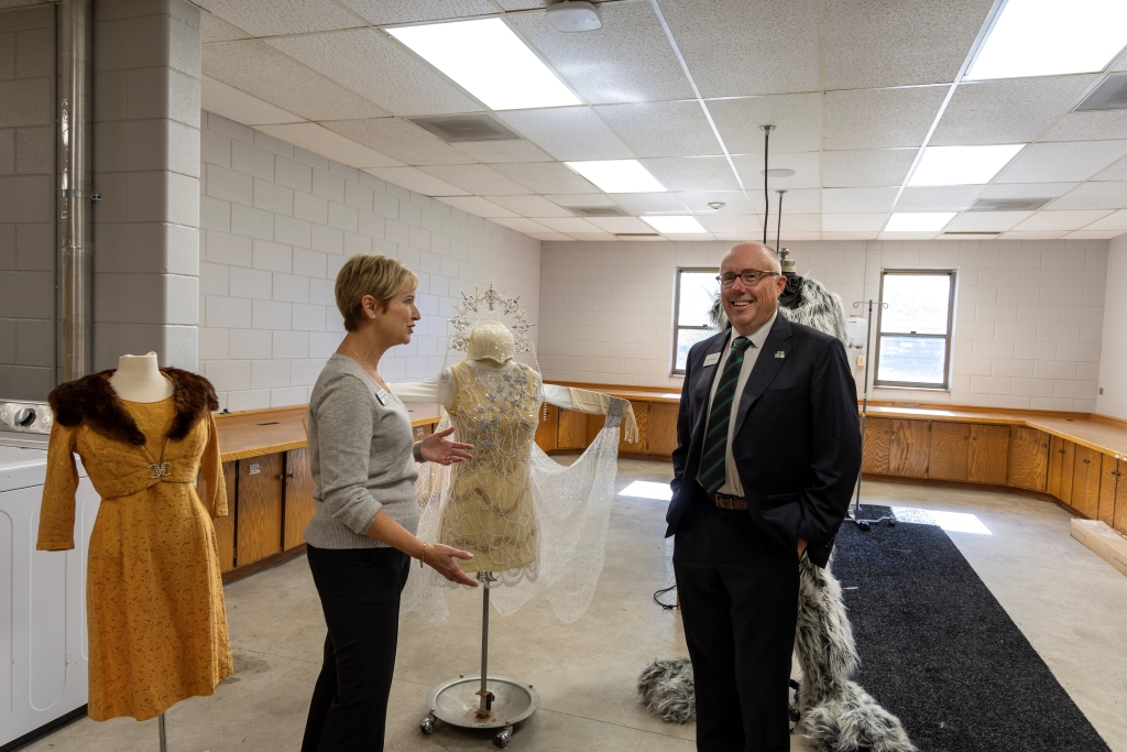 Dean Rundquist and Tami Carmichael talk beside a display of costumes during the UND Theatre open house.