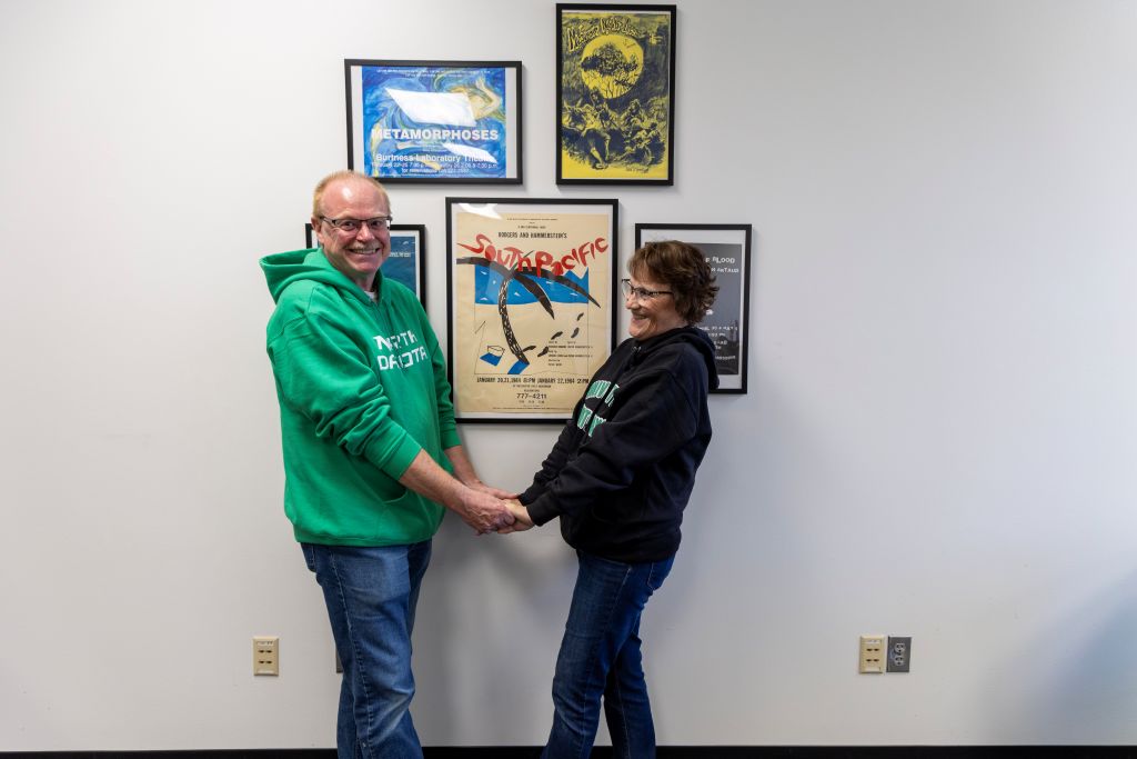Perri and Shelia Nagel stand together in front of a “South Pacific” production poster.